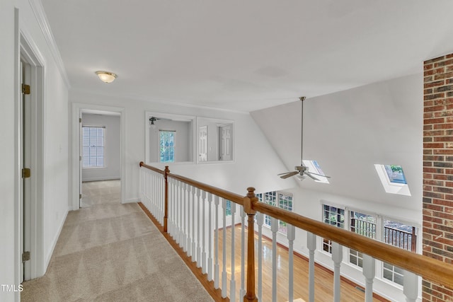 hall featuring light colored carpet, baseboards, and lofted ceiling with skylight