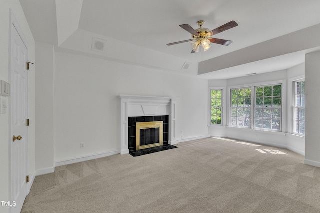 unfurnished living room featuring a tiled fireplace, carpet flooring, baseboards, and ceiling fan