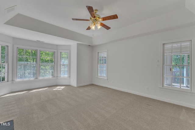 empty room with ceiling fan, baseboards, a tray ceiling, and carpet floors