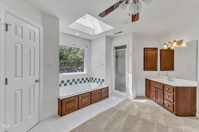 bathroom featuring a ceiling fan, a skylight, a bath, vanity, and visible vents
