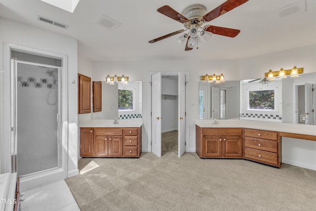 bathroom featuring two vanities, baseboards, visible vents, a shower stall, and ceiling fan