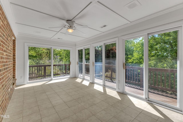 unfurnished sunroom featuring brick wall, a ceiling fan, visible vents, and tile patterned floors