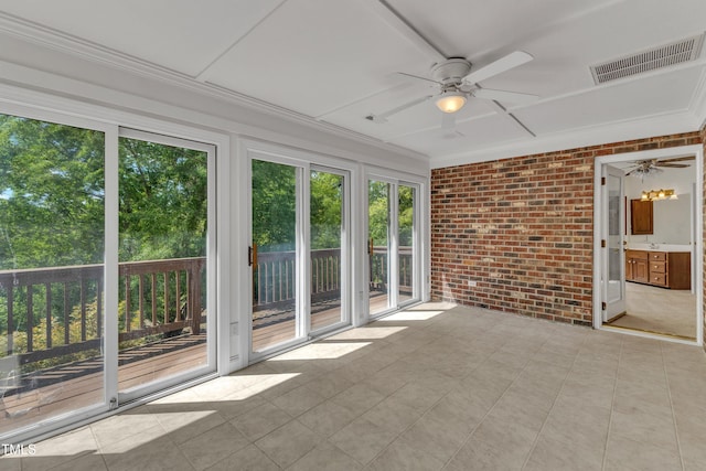 unfurnished sunroom featuring brick wall, visible vents, plenty of natural light, and crown molding