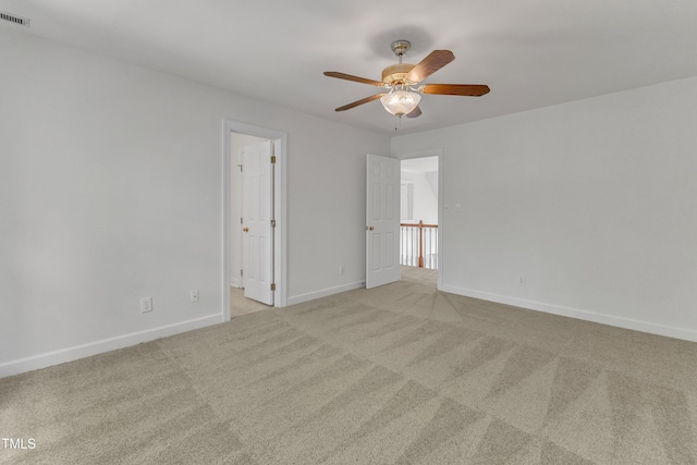 unfurnished room featuring light carpet, a ceiling fan, visible vents, and baseboards