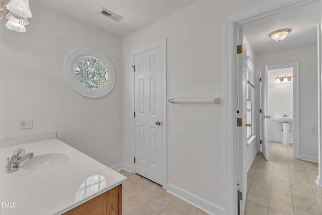 bathroom with tile patterned flooring, baseboards, visible vents, and a sink