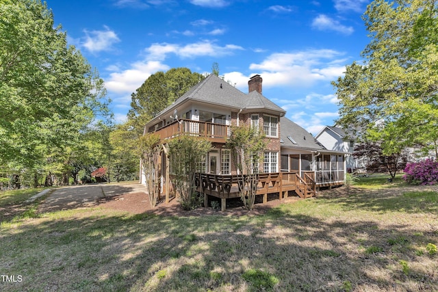 back of house with a chimney, a wooden deck, a sunroom, and a yard