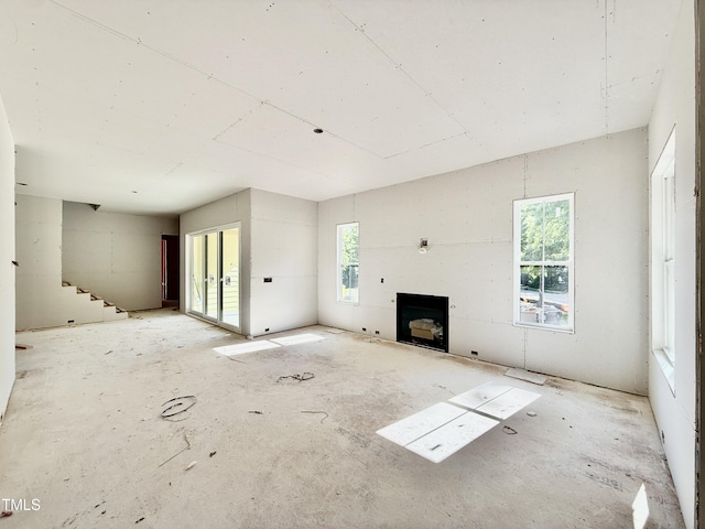 unfurnished living room featuring stairs and a fireplace