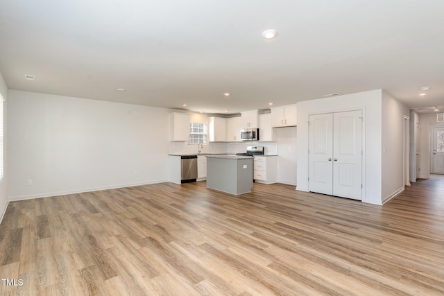 kitchen featuring a kitchen island, light wood-style flooring, appliances with stainless steel finishes, open floor plan, and white cabinetry