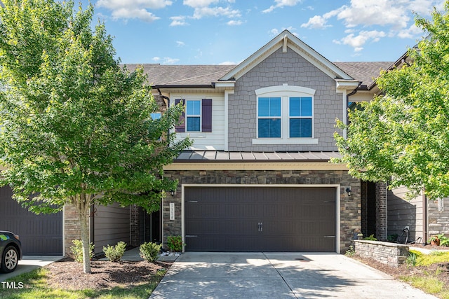 view of front of home with a garage, stone siding, a standing seam roof, metal roof, and driveway
