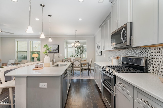 kitchen with gray cabinets, a breakfast bar area, a sink, dark wood-style floors, and stainless steel appliances