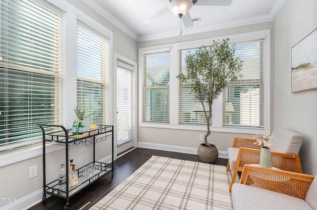 living area with dark wood-type flooring, ornamental molding, baseboards, and ceiling fan