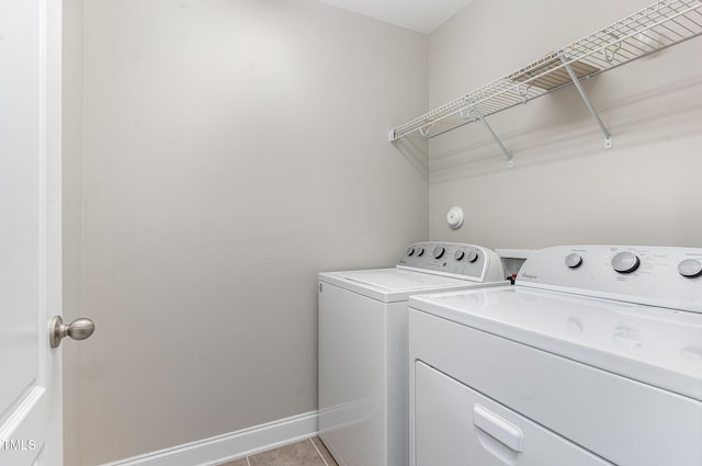 washroom featuring light tile patterned floors, separate washer and dryer, baseboards, and laundry area