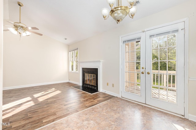 unfurnished living room featuring ceiling fan with notable chandelier, french doors, visible vents, a fireplace with flush hearth, and lofted ceiling