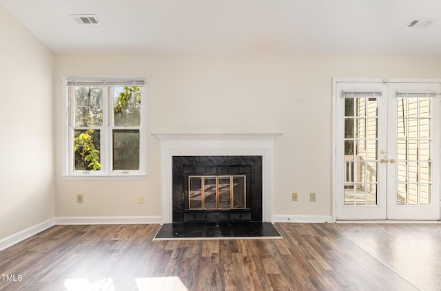 unfurnished living room featuring visible vents, french doors, baseboards, a glass covered fireplace, and wood finished floors