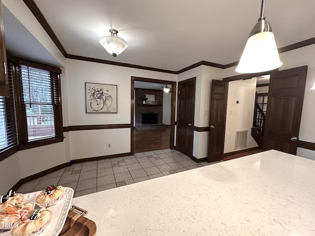 2708 Halfhitch Trl, Raleigh, NC 27615 - unfurnished dining area featuring light tile patterned flooring, baseboards, a ceiling fan, ornamental molding, and a brick fireplace
