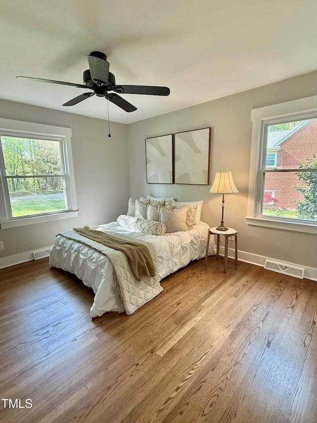 bedroom with baseboards, wood finished floors, visible vents, and ceiling fan
