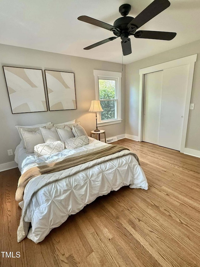 bedroom featuring baseboards, a ceiling fan, wood finished floors, and a closet