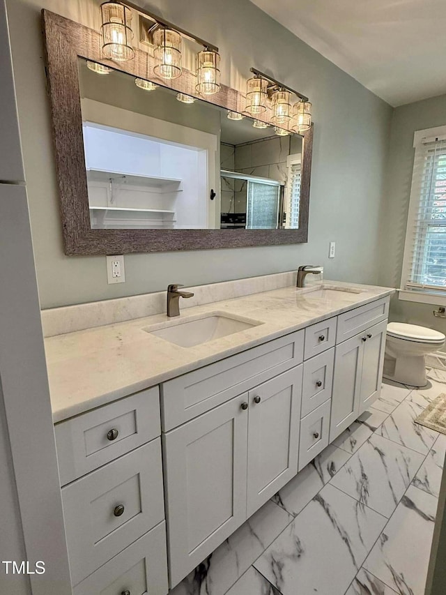 full bathroom featuring a shower stall, a sink, marble finish floor, double vanity, and toilet