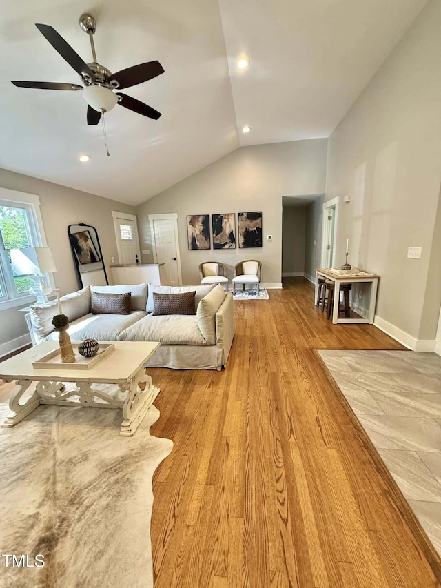 living room with baseboards, lofted ceiling, a ceiling fan, and light wood-type flooring