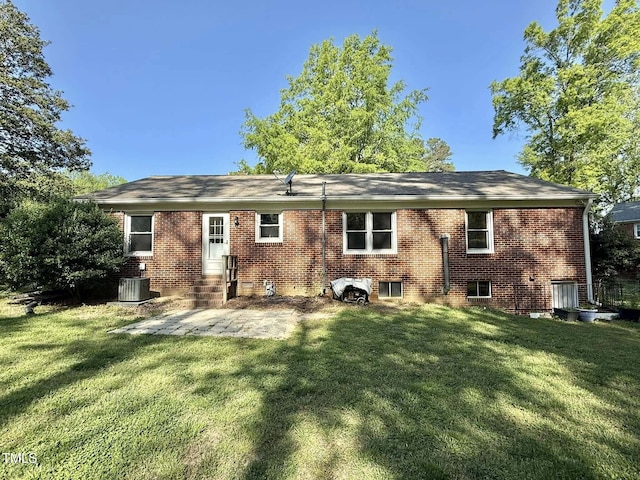 rear view of property featuring central AC unit, entry steps, a patio area, a lawn, and brick siding