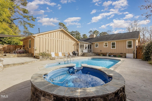 view of pool featuring a pool with connected hot tub, fence, and a patio