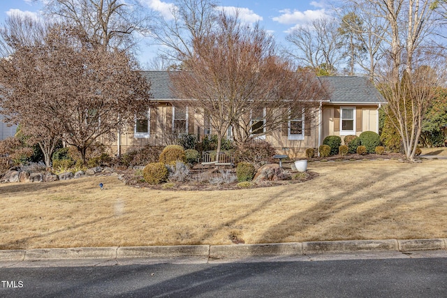 ranch-style home with a front yard and roof with shingles