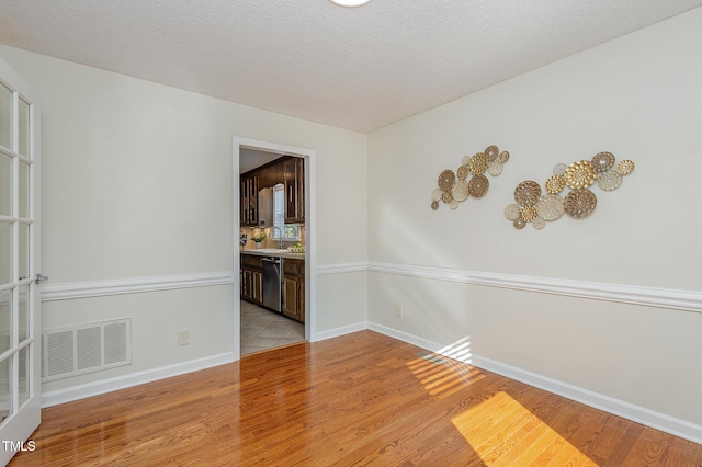 empty room with a sink, visible vents, baseboards, and light wood-type flooring