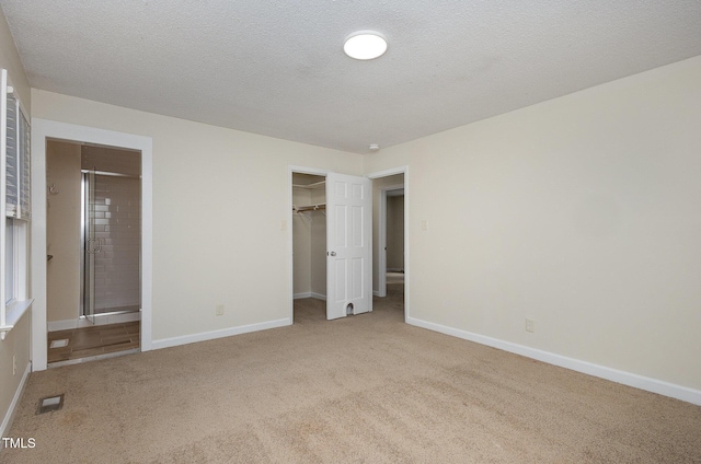 unfurnished bedroom featuring connected bathroom, baseboards, visible vents, and carpet