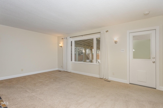 carpeted empty room featuring a textured ceiling, baseboards, and visible vents