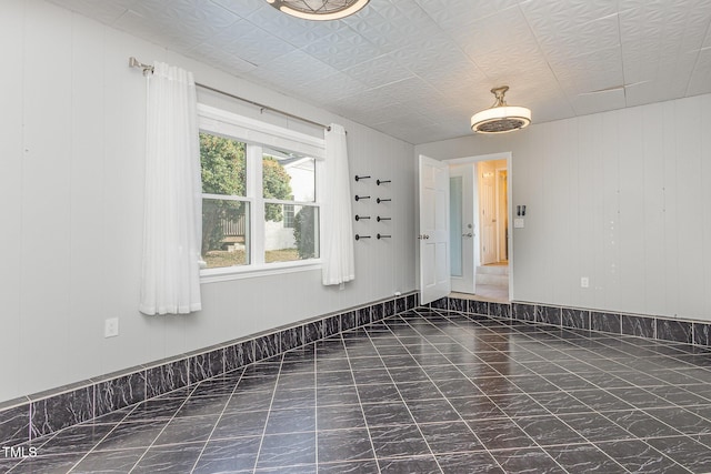 spare room featuring wood walls and marble finish floor