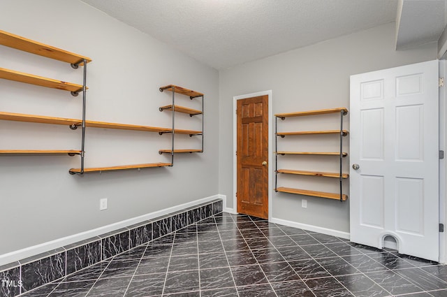 interior space featuring baseboards, marble finish floor, and a textured ceiling