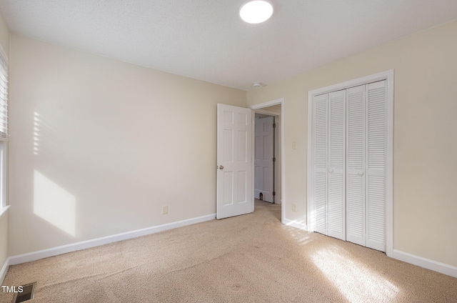 unfurnished bedroom featuring a closet, carpet flooring, baseboards, and visible vents