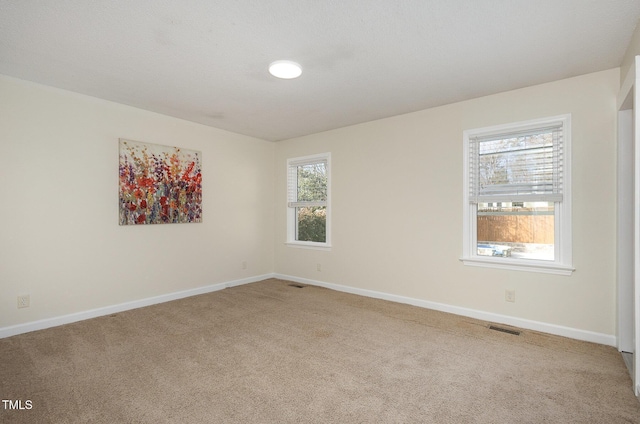 carpeted empty room featuring baseboards and visible vents