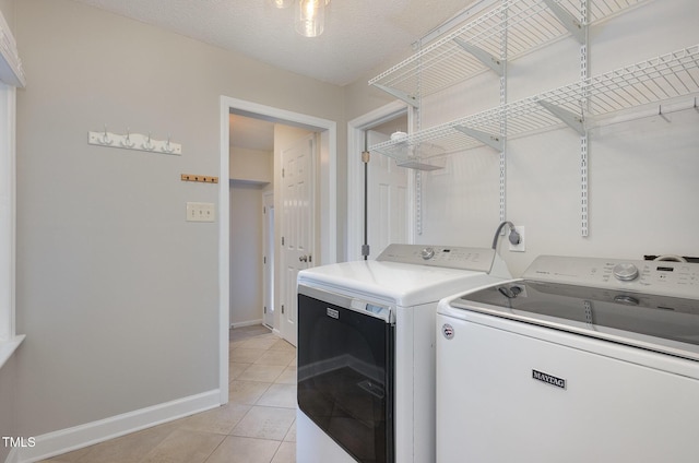 laundry area with washing machine and dryer, laundry area, baseboards, and light tile patterned flooring