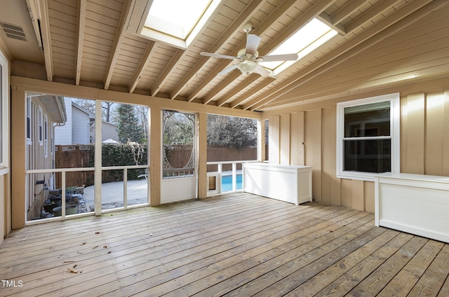 unfurnished sunroom with a skylight, beam ceiling, a ceiling fan, and visible vents