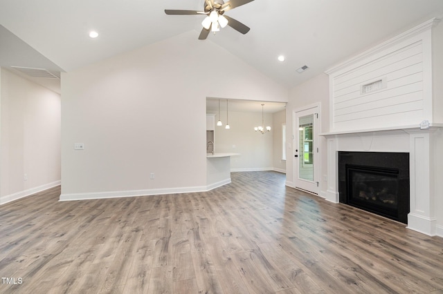 1000 Peedin Rd, Selma, NC 27576 - unfurnished living room featuring high vaulted ceiling, ceiling fan, a chandelier, wood finished floors, and a glass covered fireplace