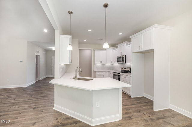 1000 Peedin Rd, Selma, NC 27576 - kitchen with appliances with stainless steel finishes, a peninsula, wood finished floors, hanging light fixtures, and white cabinetry