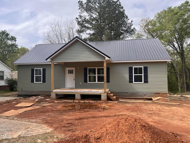 view of front of home with crawl space, a porch, and metal roof