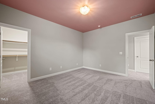 unfurnished bedroom featuring baseboards, carpet, a spacious closet, and visible vents