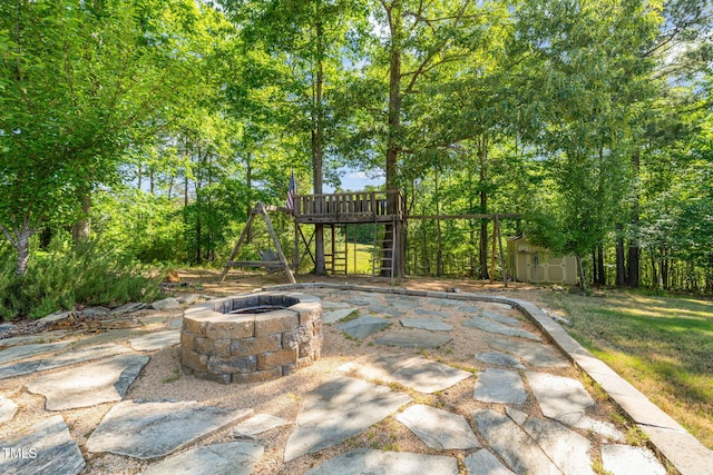 view of patio with an outdoor structure, an outdoor fire pit, and a storage shed