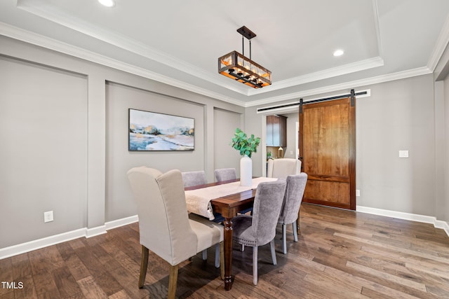 dining area featuring ornamental molding, wood finished floors, baseboards, a barn door, and a tray ceiling