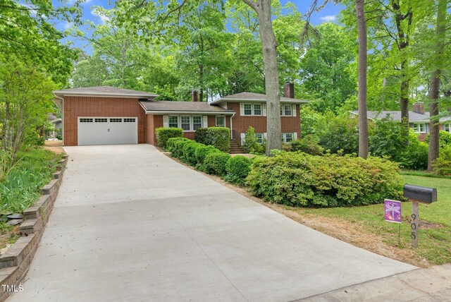 905 Cindy St, Cary, NC 27511 - tri-level home with brick siding, a garage, a chimney, and concrete driveway