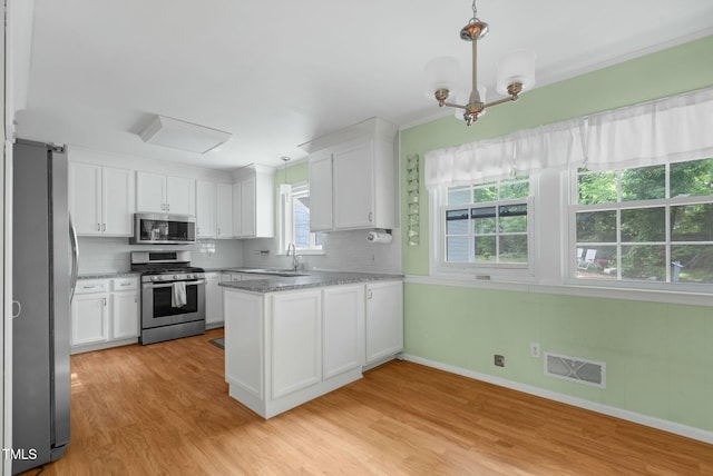 905 Cindy St, Cary, NC 27511 - kitchen featuring decorative backsplash, visible vents, appliances with stainless steel finishes, light wood-type flooring, and white cabinetry