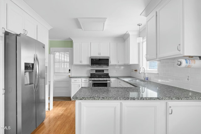 905 Cindy St, Cary, NC 27511 - kitchen featuring white cabinets, appliances with stainless steel finishes, a sink, a peninsula, and a healthy amount of sunlight