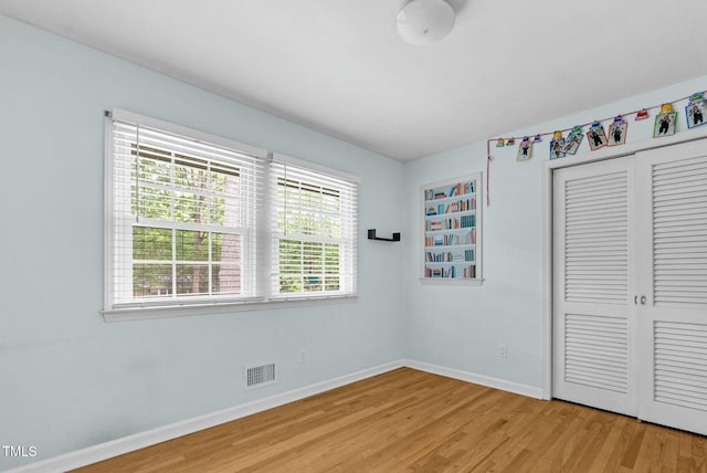 905 Cindy St, Cary, NC 27511 - unfurnished bedroom featuring baseboards, multiple windows, a closet, and light wood-type flooring