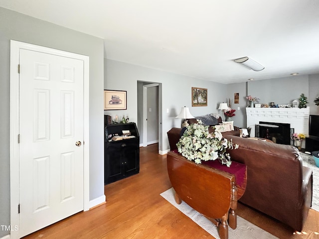 107 N Pearl St, Princeton, NC 27569 - living room with light wood-type flooring, a brick fireplace, and baseboards