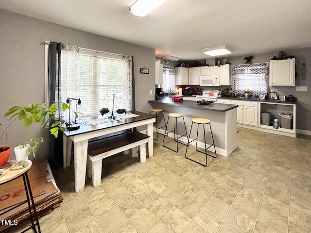 107 N Pearl St, Princeton, NC 27569 - kitchen with white appliances, dark countertops, white cabinets, a kitchen bar, and a peninsula