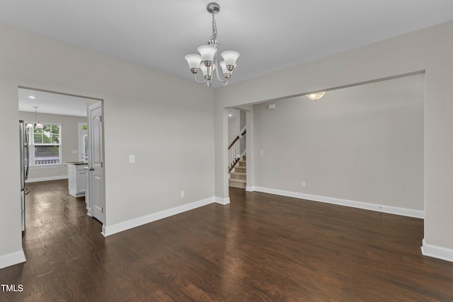 empty room featuring stairway, an inviting chandelier, dark wood-style floors, and baseboards