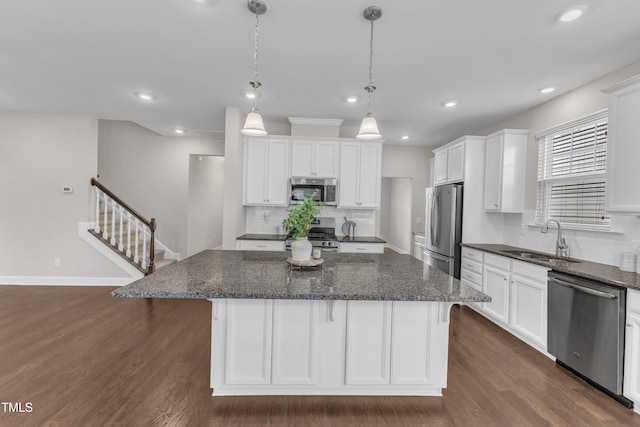 kitchen with stainless steel appliances, a center island, a sink, and dark wood finished floors