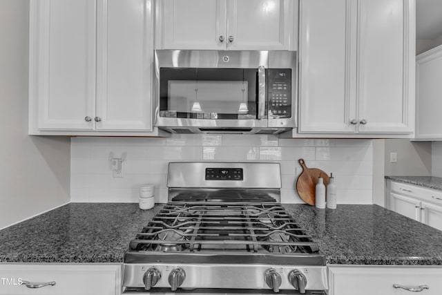 kitchen with decorative backsplash, appliances with stainless steel finishes, dark stone countertops, and white cabinetry